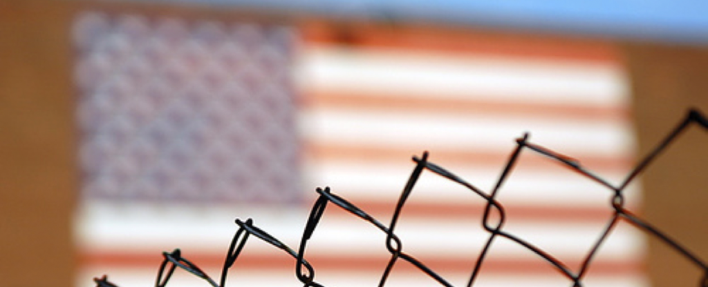 AMERICAN FLAG BEHIND A CHAIN LINK FFENCE